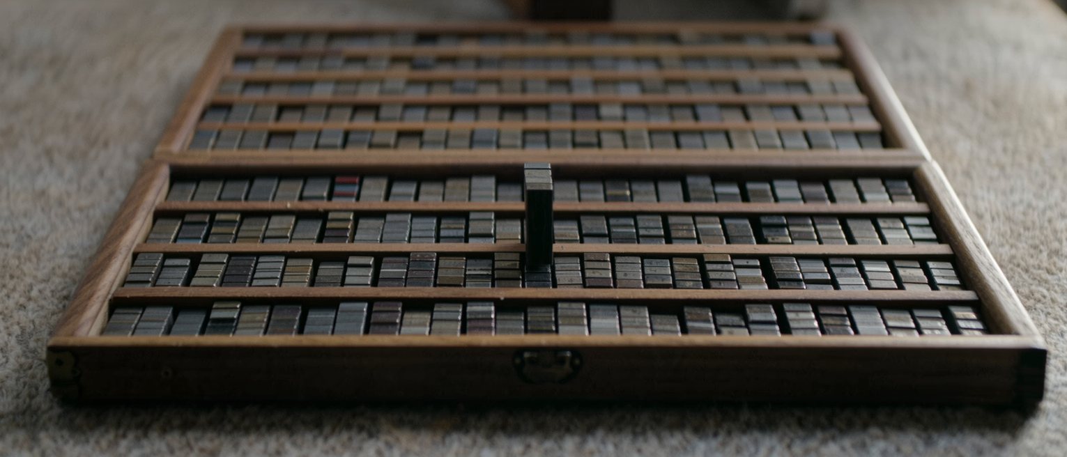 a printer's wooden type case, every compartment packed to the brim with metal type but one standing empty