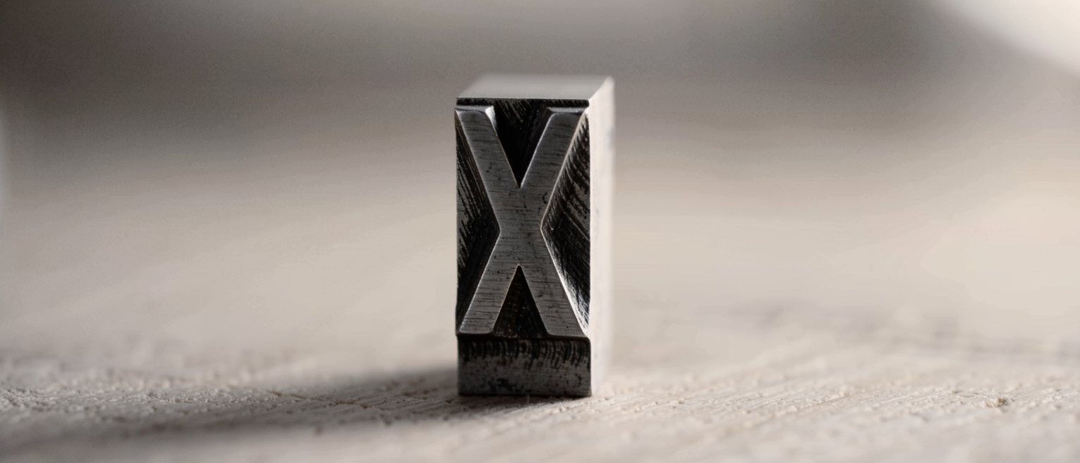 a single letterpress metal sort standing alone on its foot, one character cast in relief