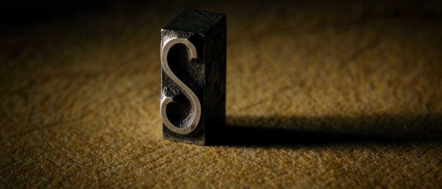 a single letterpress metal sort standing alone on its foot, one character cast in relief