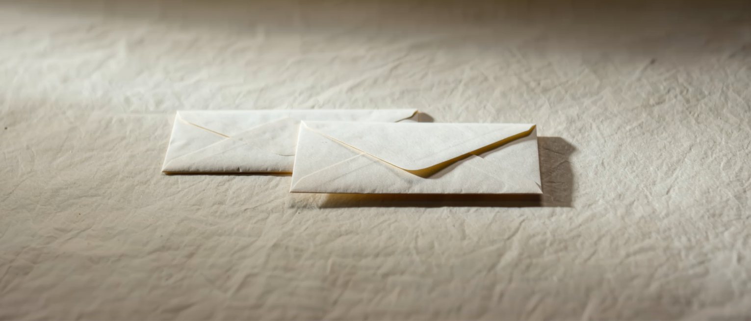 two envelopes on a table, one sealed and one still open