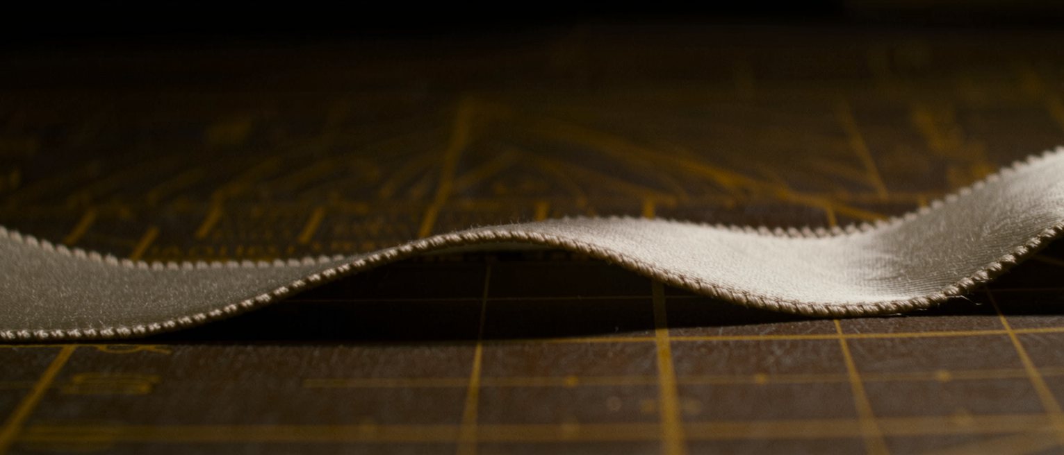 a bolt of stiff costume satin half unrolled on a cutting table, the selvedge crisp