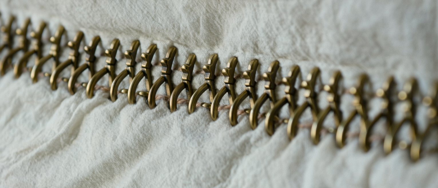 a row of brass hooks and eyes sewn down a closed seam, every one of them fastened