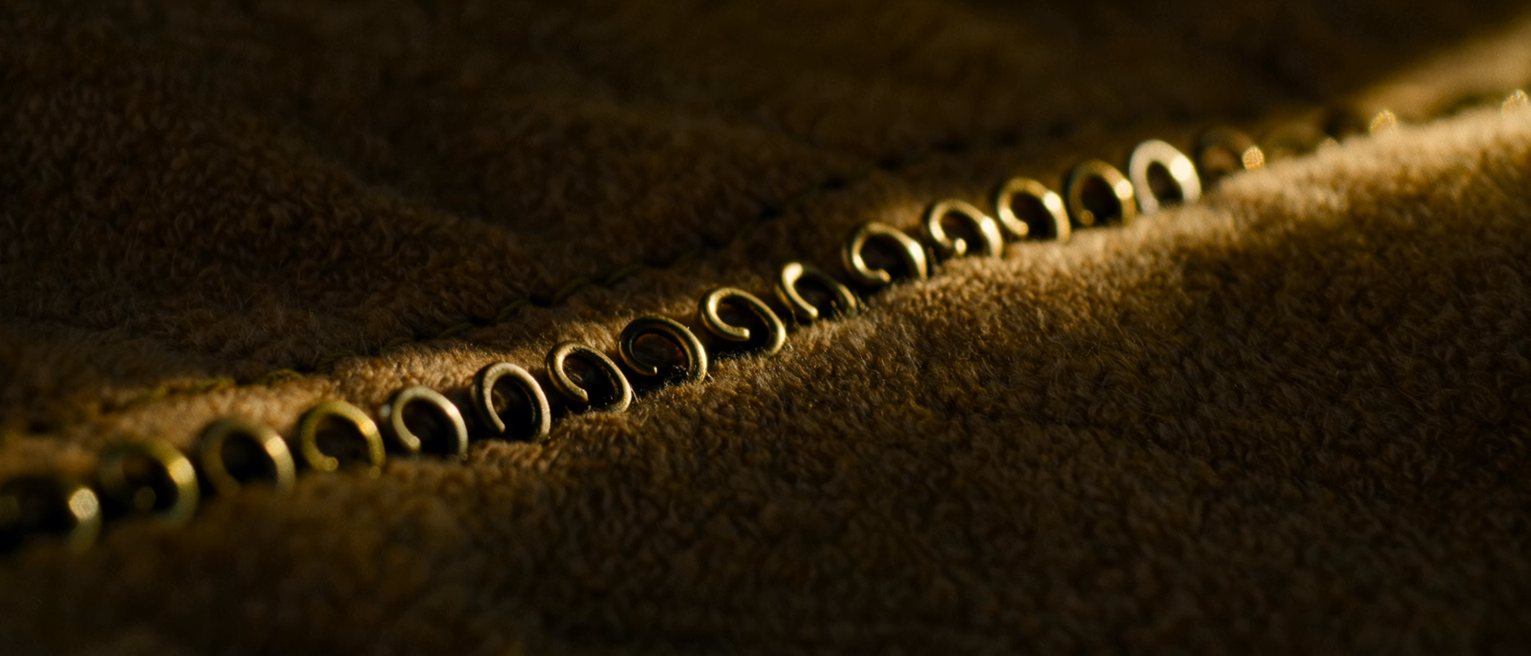 a row of brass hooks and eyes sewn down a closed seam, every one of them fastened