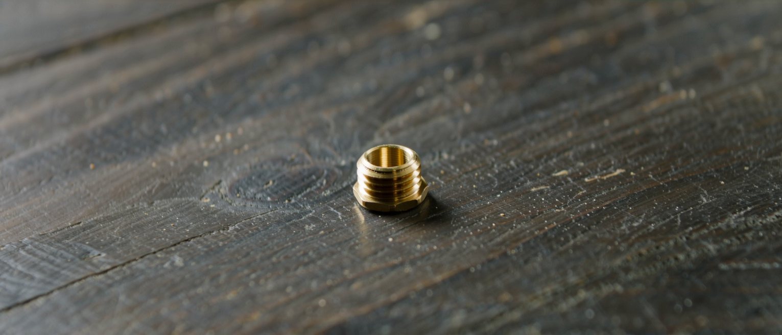 a new brass fitting screwed onto an old blackened timber, the metal still bright