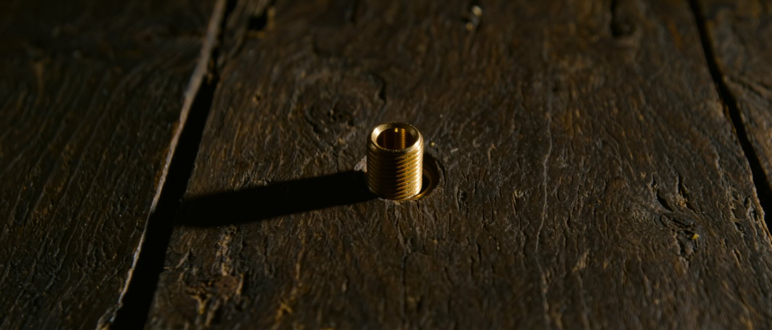 a new brass fitting screwed onto an old blackened timber, the metal still bright
