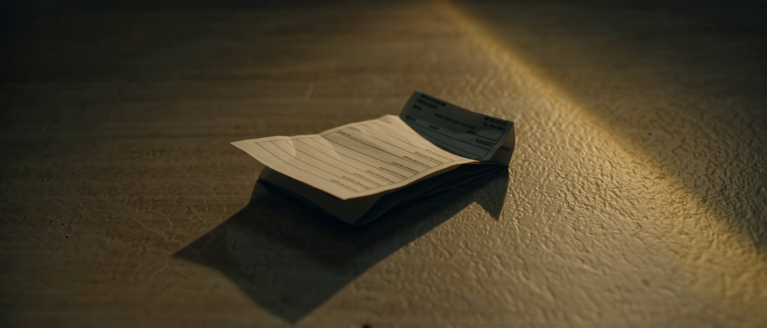 an itemised paper account folded once and left face down on a counter, the corner curling up