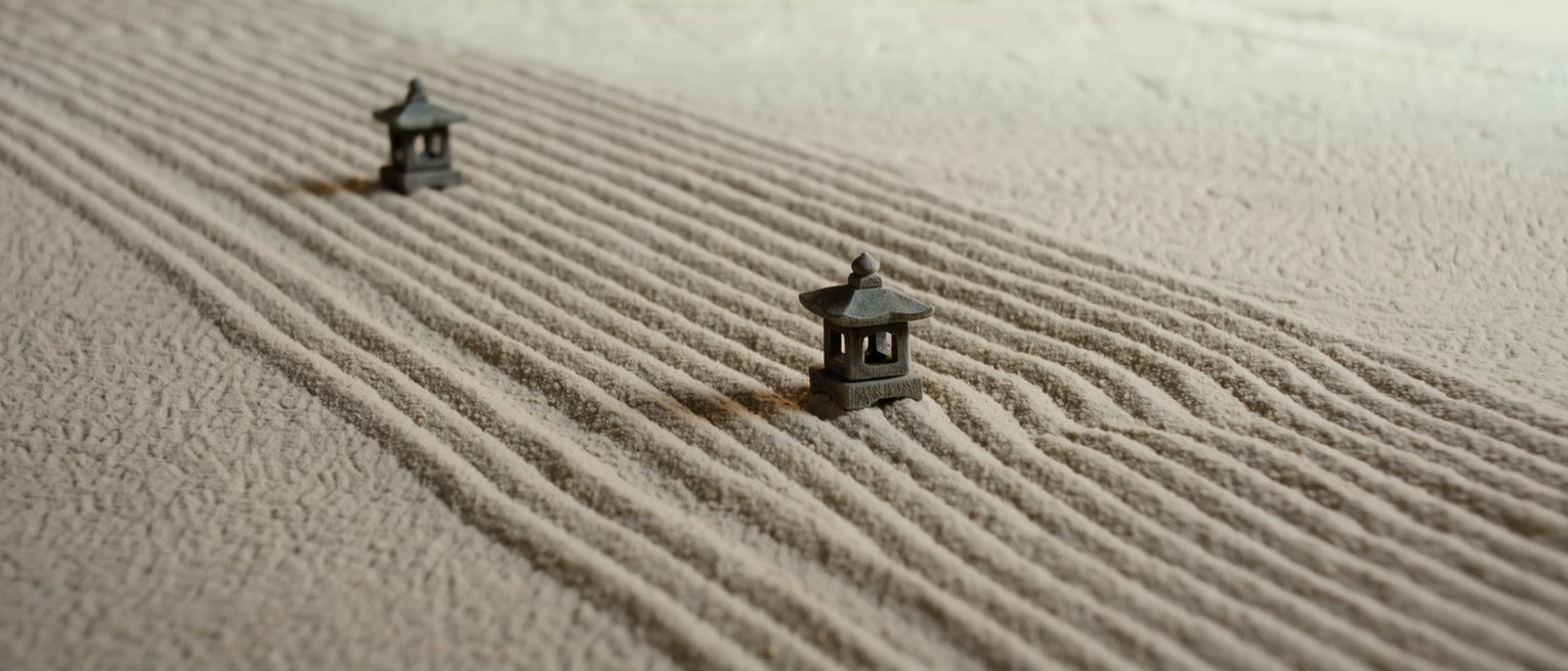 two stone lanterns set far apart along a path, the ground between them raked