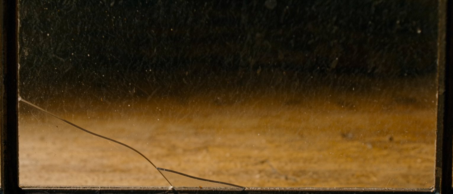 a pane of glass with a single crack running corner to corner, still in its frame