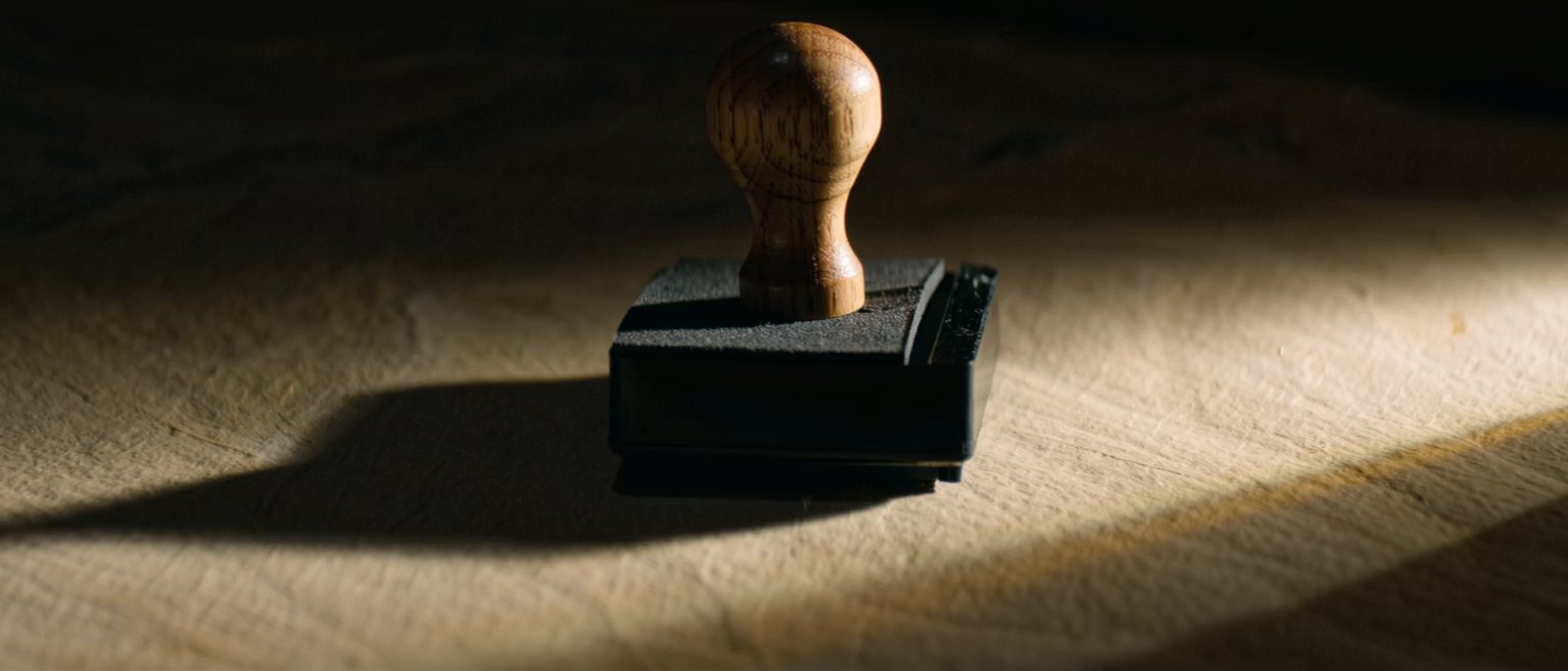 a wooden-handled rubber stamp resting on its ink pad, the rubber pad uncut and blank