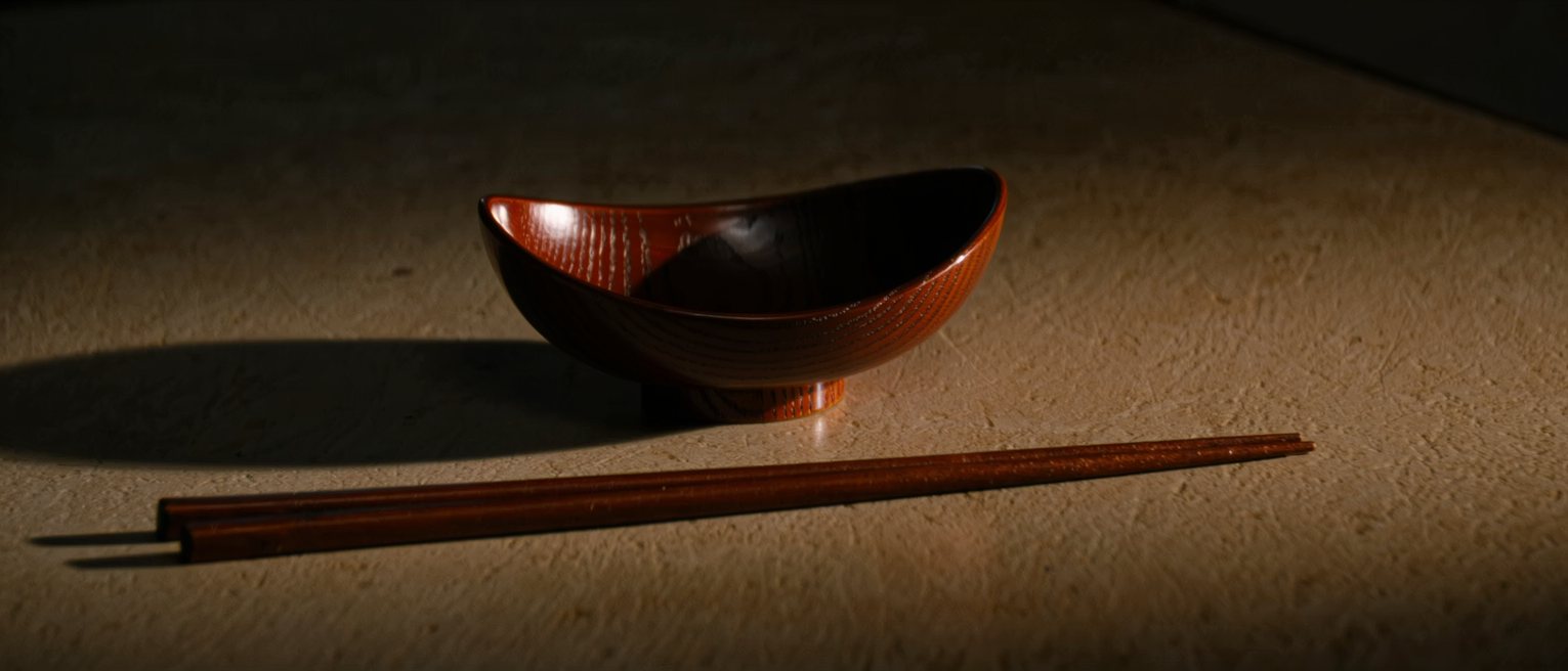 one lacquer bowl and one pair of chopsticks set down on a long bare table
