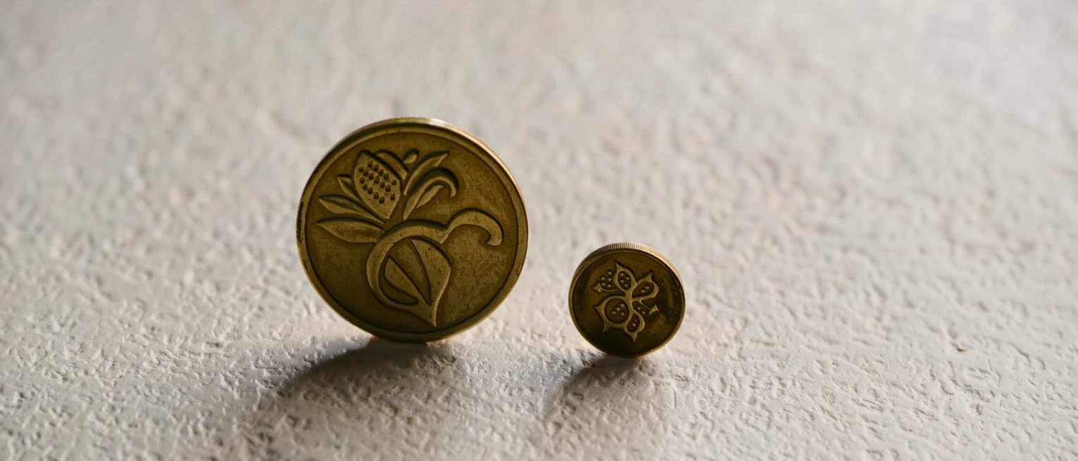 two separate brass tokens of different sizes lying on a counter