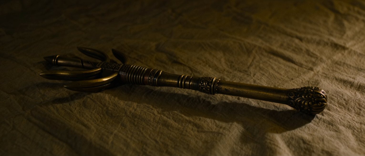 a bronze five-pronged Buddhist vajra sceptre lying full length on a folded cloth, its prongs curved in and closed at each end