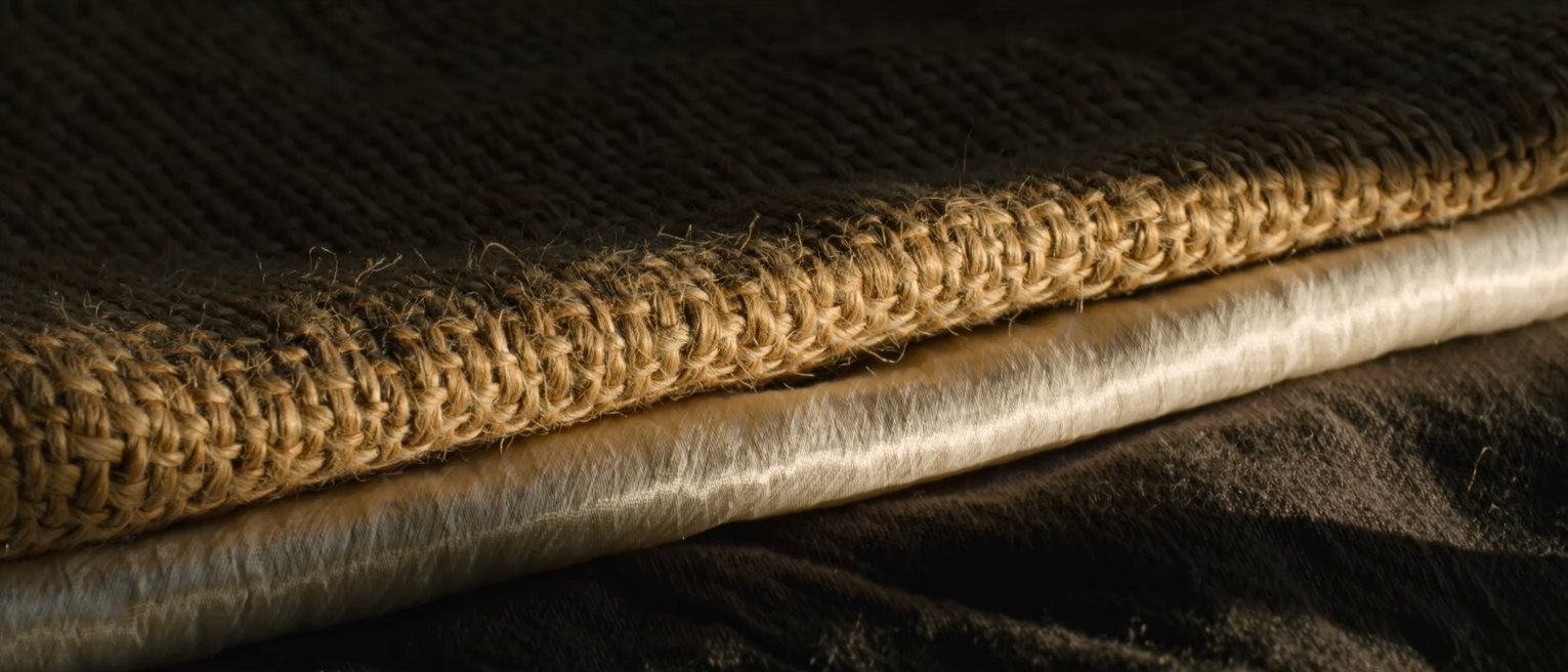 three different cloths laid one across another, a coarse linen, a thick wool and a fine silk