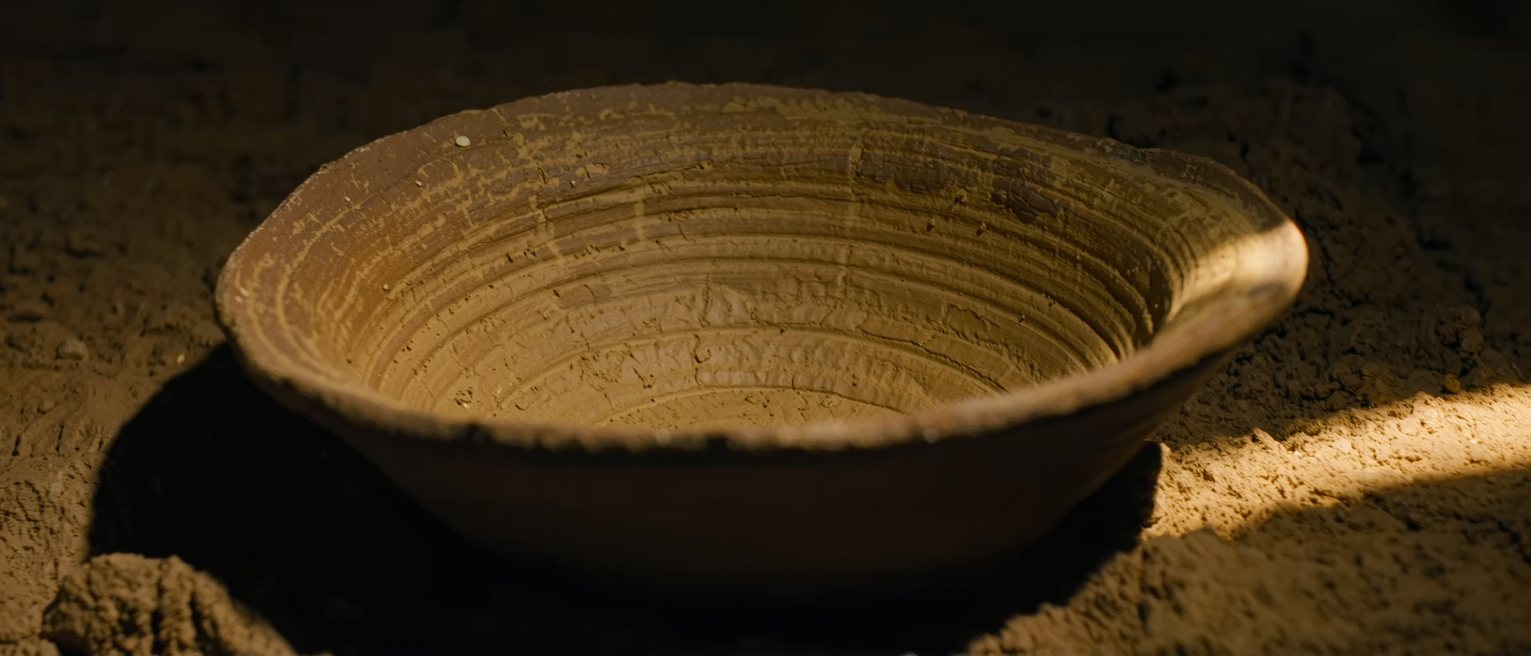 a hand-thrown clay bowl with the potter's finger ridges standing inside it