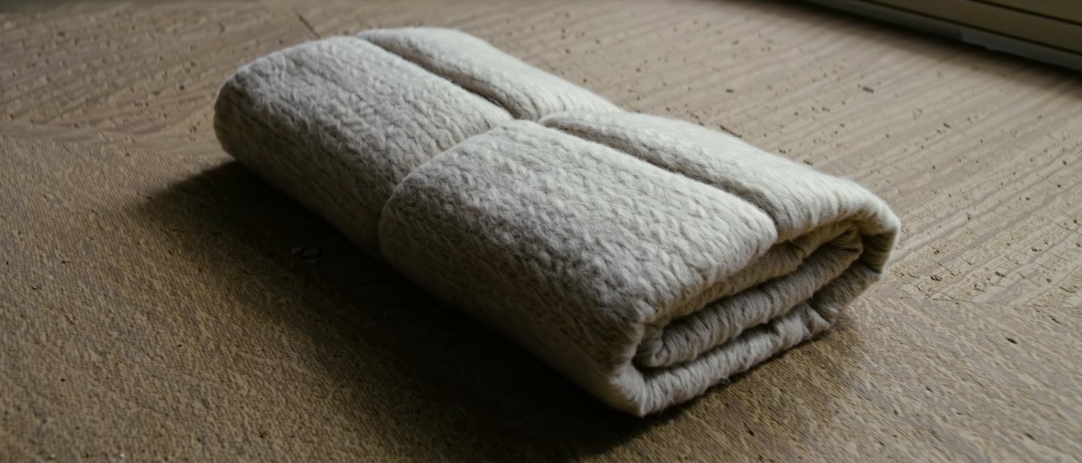 a wool blanket folded in four on a bench, the nap brushed one way