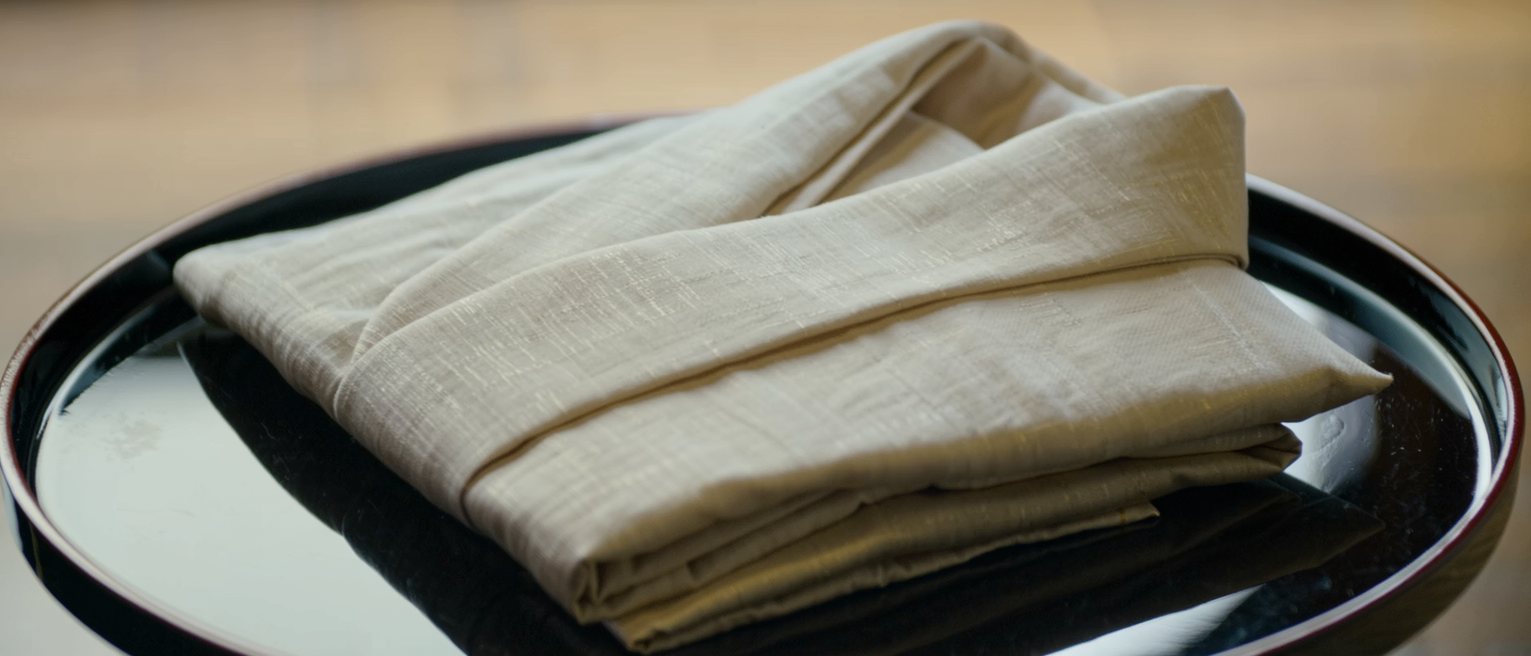 a folded yukata laid on a lacquer tray with the sash coiled beside it
