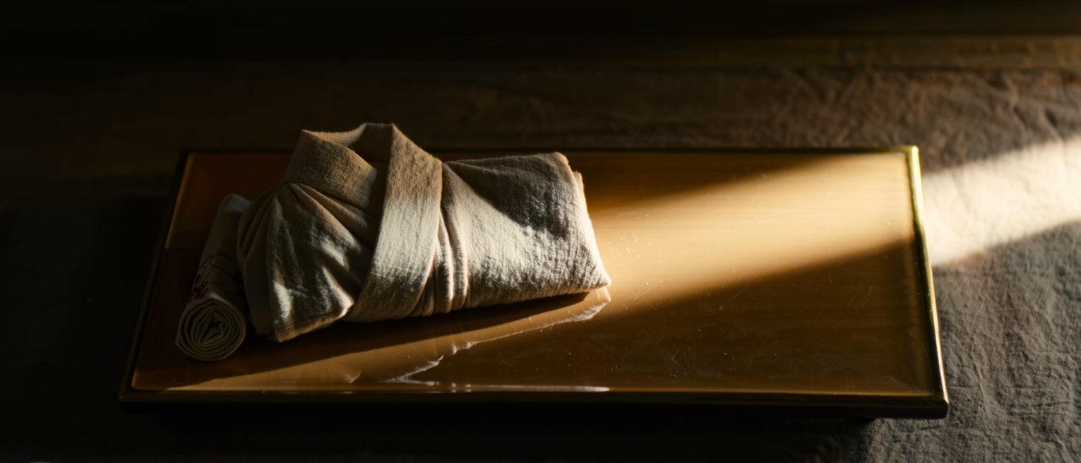 a folded yukata laid on a lacquer tray with the sash coiled beside it