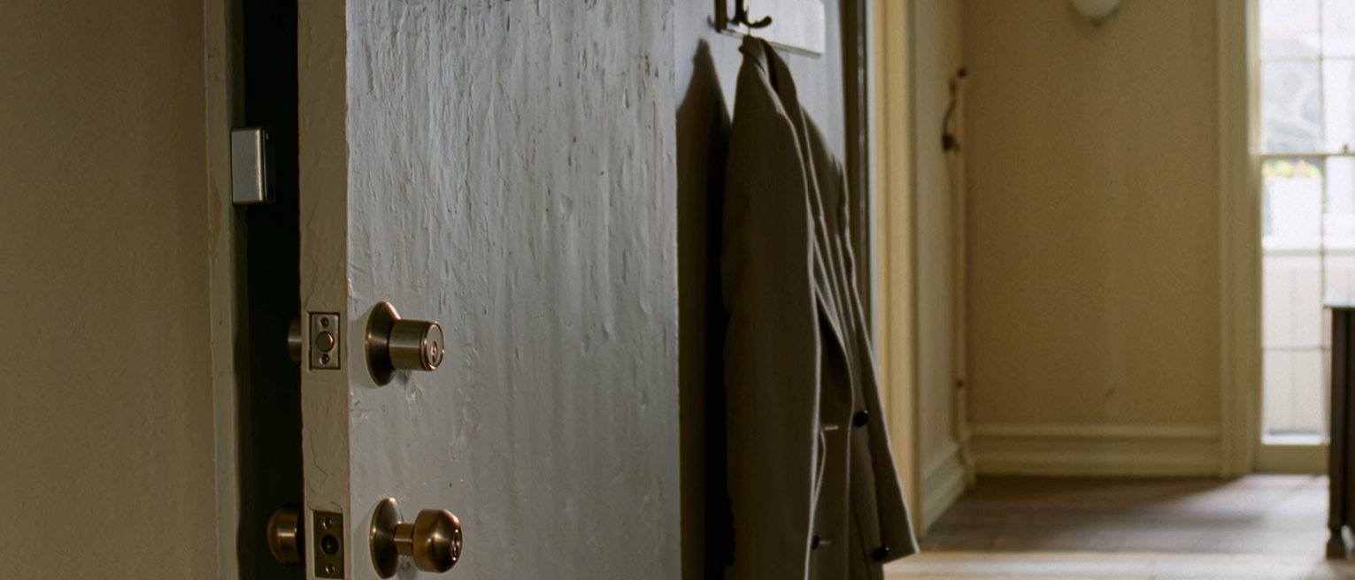 a front door with three locks, every one of them turned, and a coat hung ready on the hook beside it