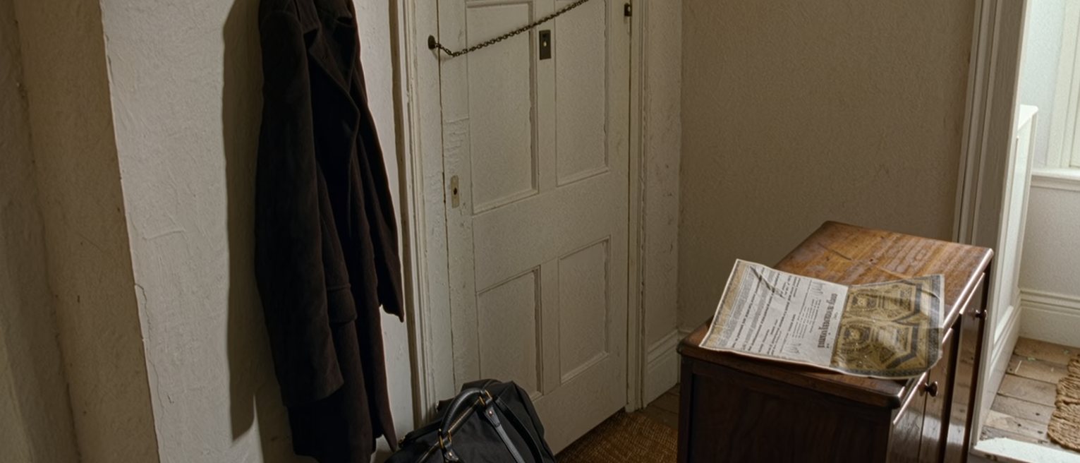 a hall seen close with a coat on the hook, a packed bag by the door and a folded decree printed from the gazette on the console, the door with its chain soft behind