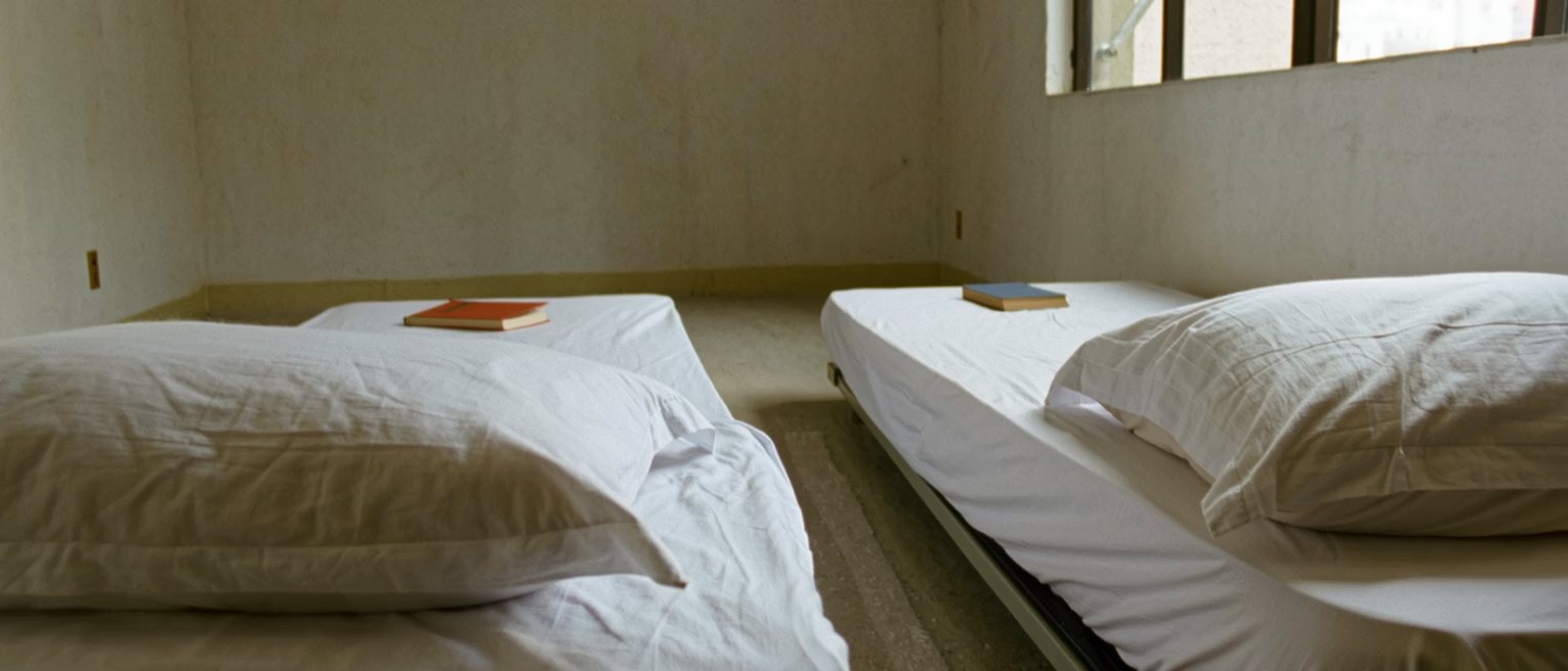 a bedroom with two single beds made up side by side, a book on each pillow, the gap between them just wide enough to step through