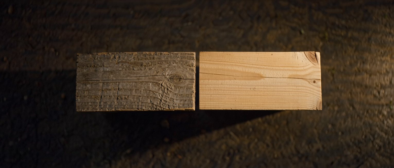two wooden signboards planed from the same plank, one weathered grey and the other still pale