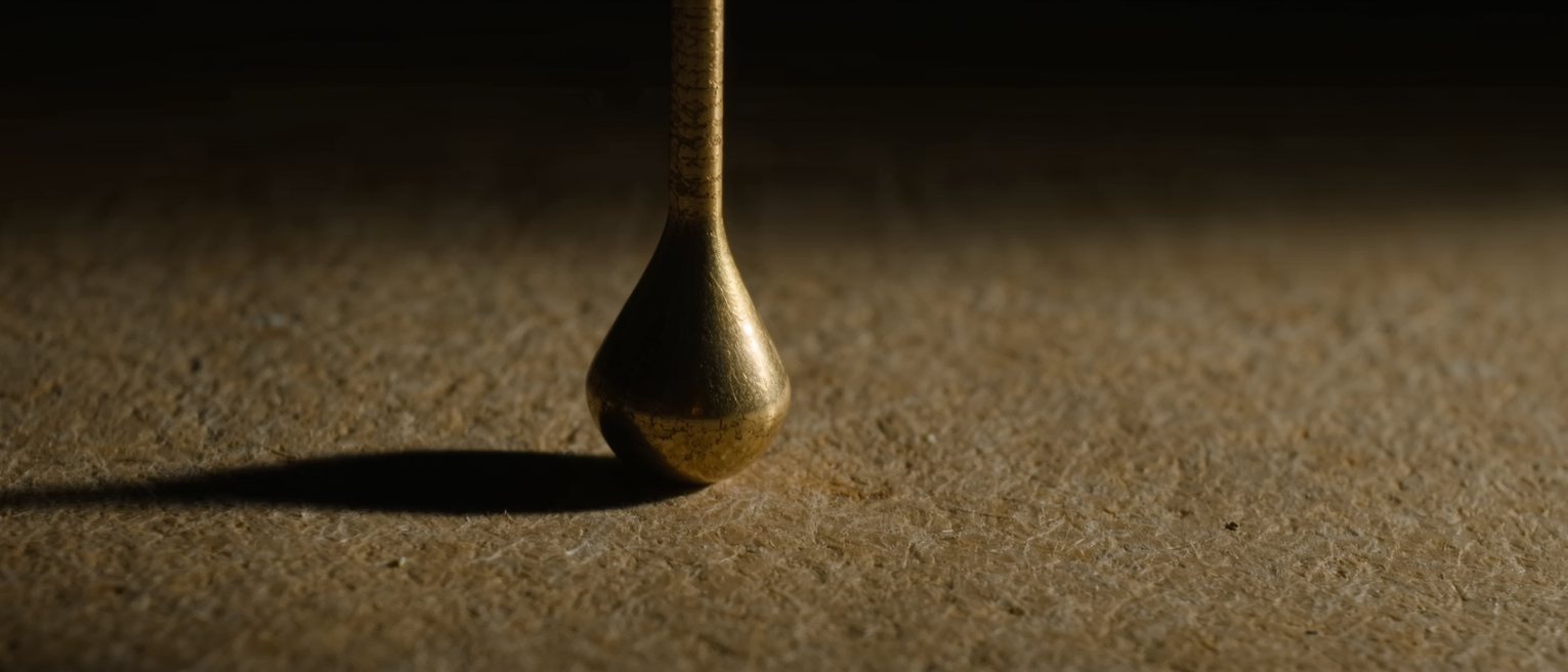 a brass plumb bob hanging still on its line