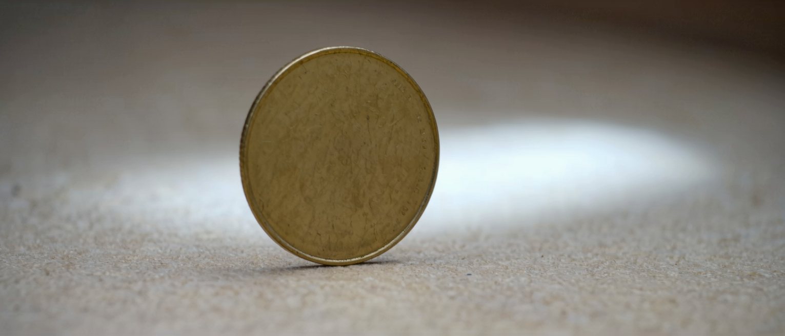 a flat brass disc standing on its edge, both blank sides catching a little of the light