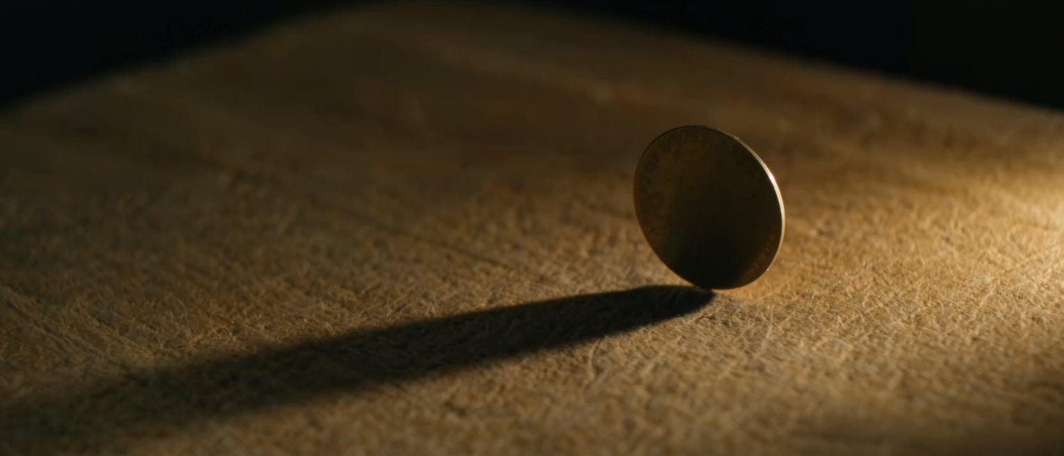 a flat brass disc standing on its edge, both blank sides catching a little of the light