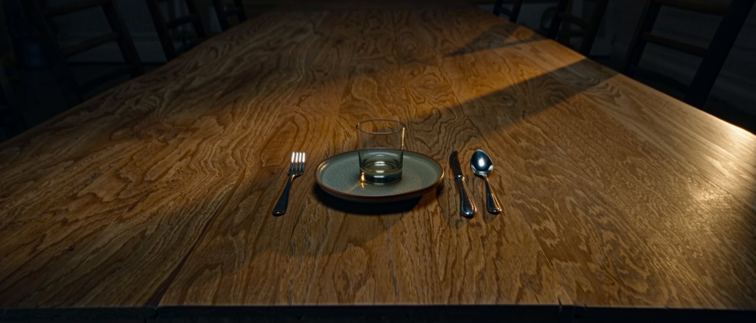one single place setting alone at the end of a long bare table
