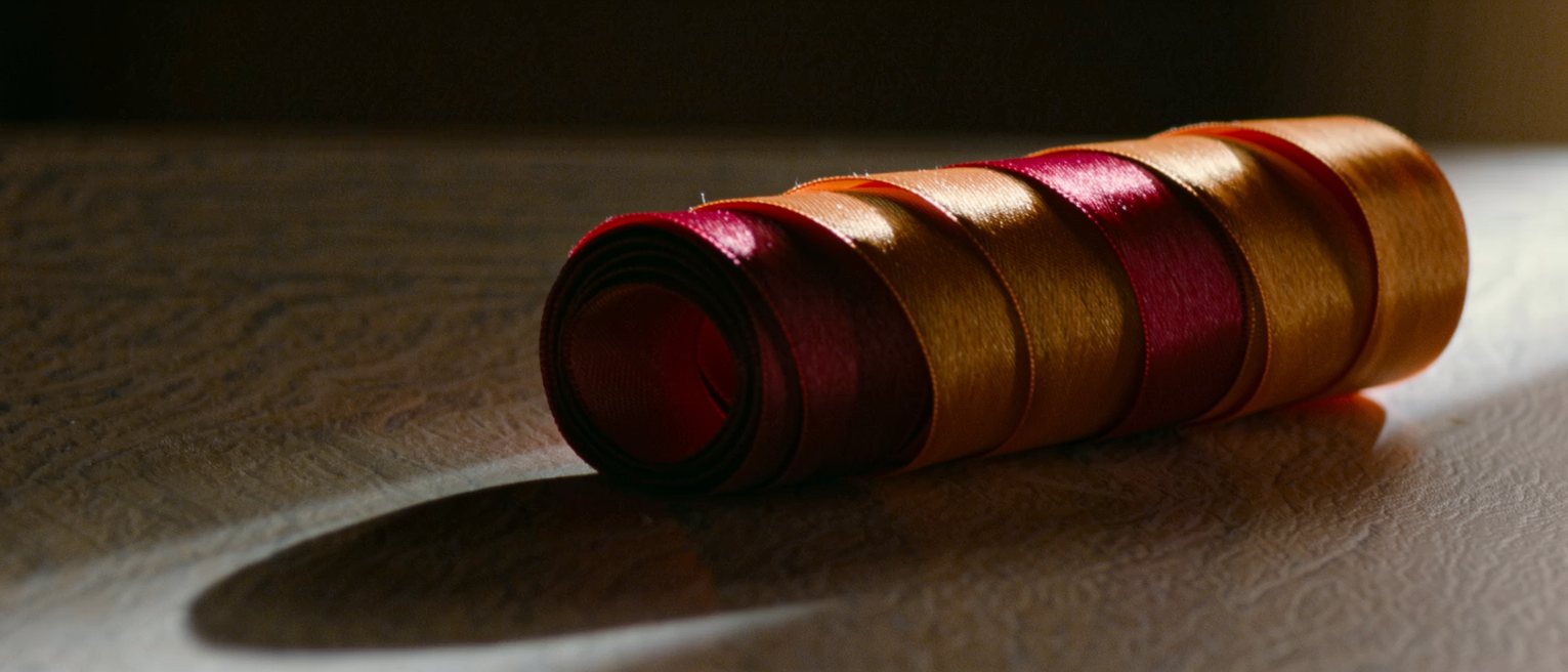 a wide satin gift ribbon curled tight and bright, lying on a table