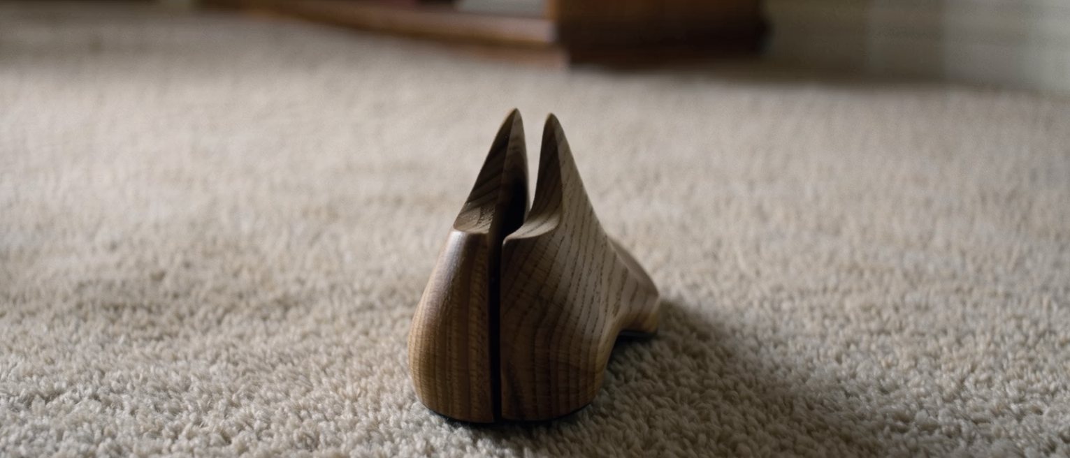 a wooden shoe last standing on a pine shelf, cut to a shape nothing in the house matches now