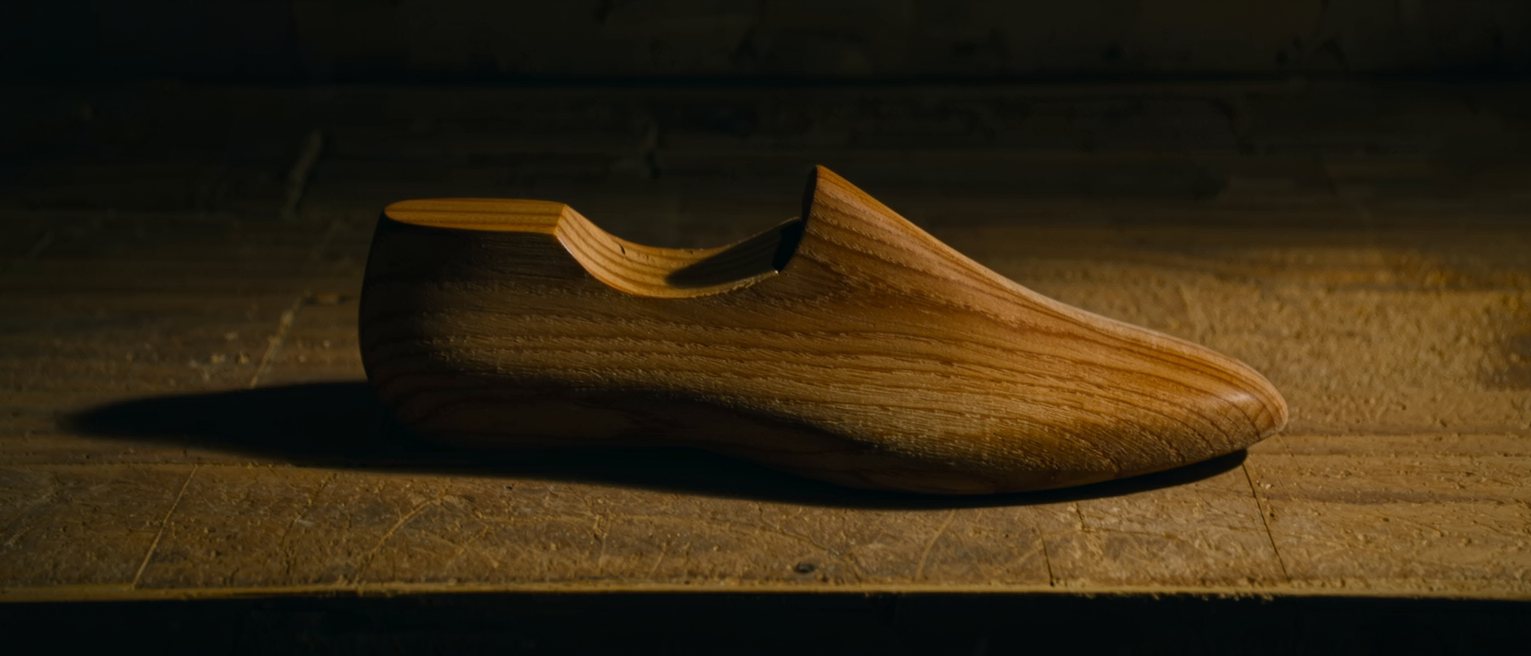 a wooden shoe last standing on a pine shelf, cut to a shape nothing in the house matches now