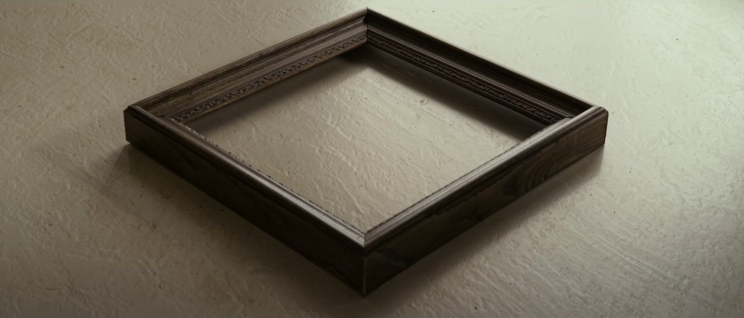 an empty picture frame of dark wood lying flat, nothing mounted in it