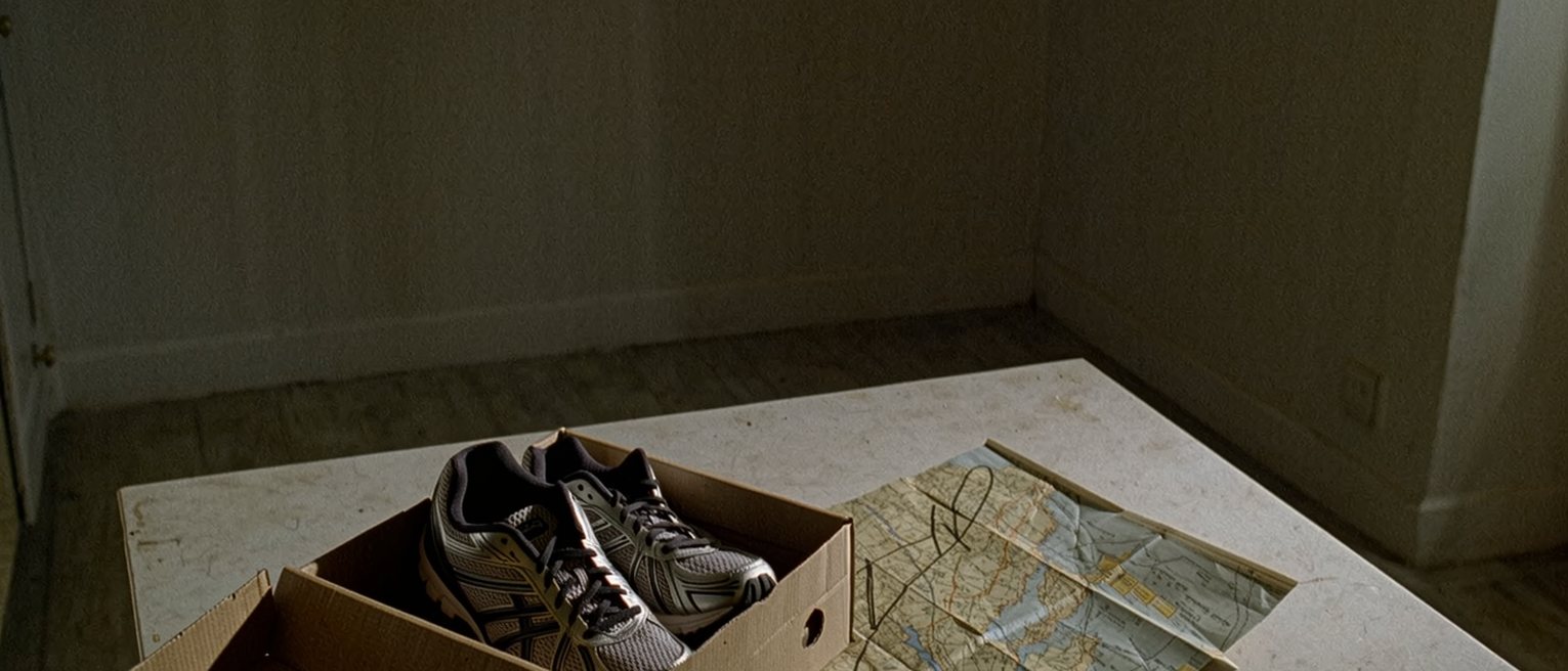 a kitchen table with a new pair of running shoes still in their box and a route pencilled on a folded map beside them