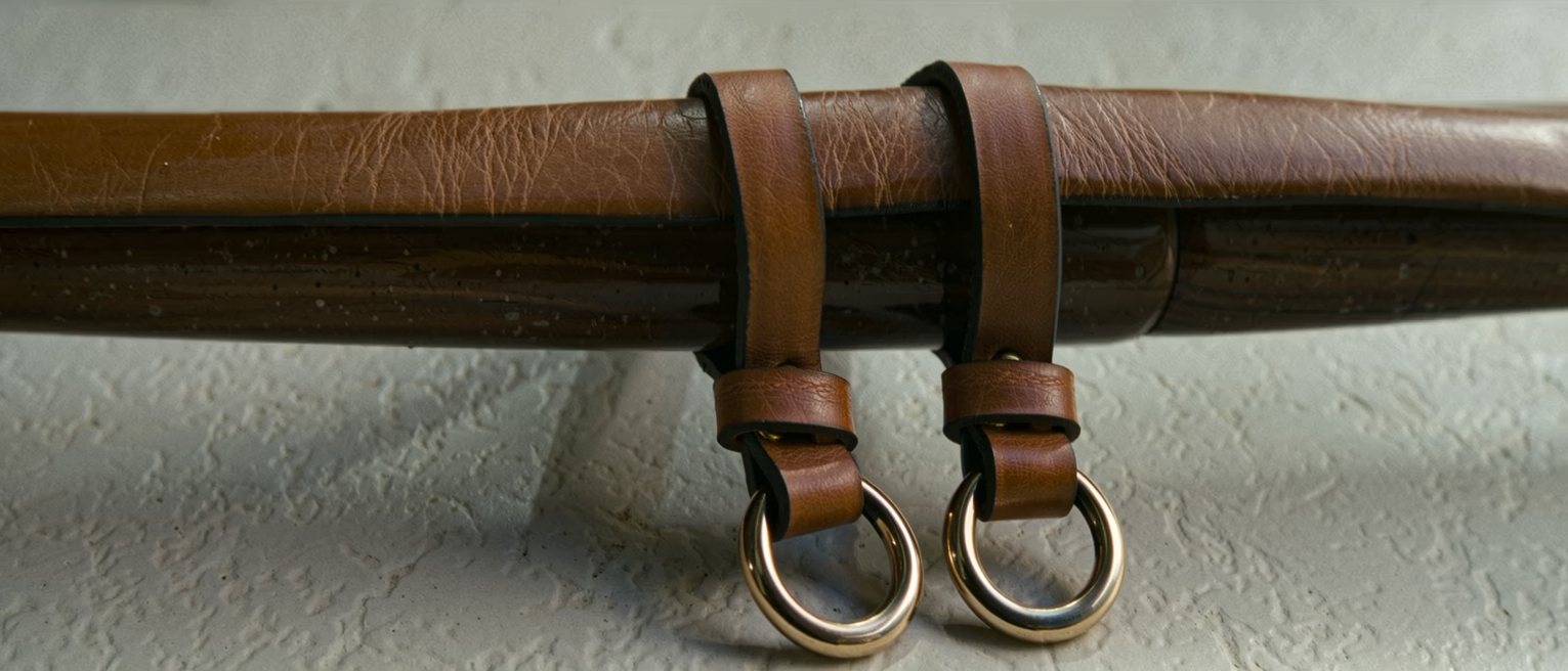 a pair of driving reins laid over a rail, the leather supple and the buckles down