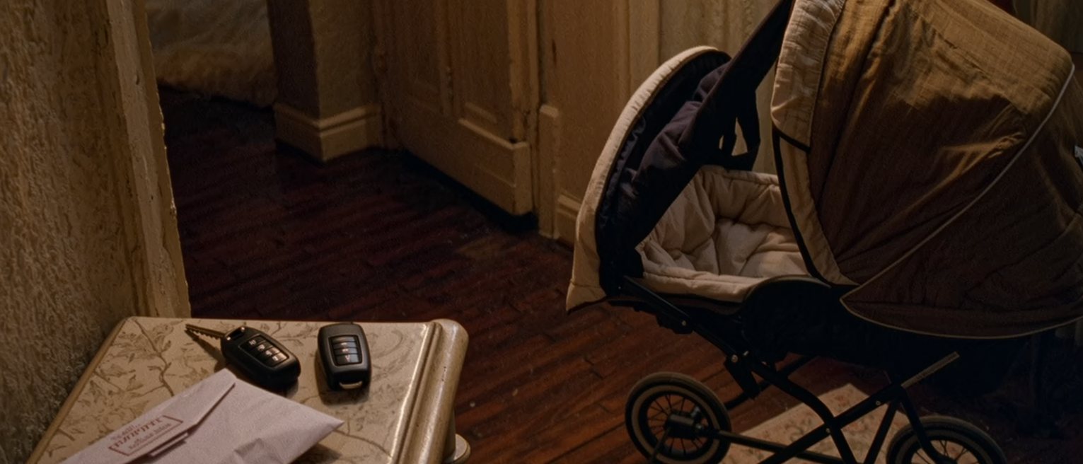 a hall table where the car keys, a waiting parcel and a folded pushchair have taken the place the flowers used to stand