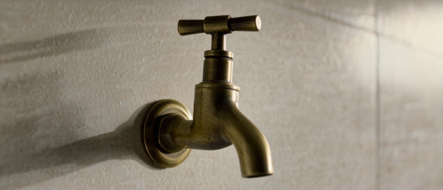a heavy brass wall tap, its handle still crisp-edged and unworn