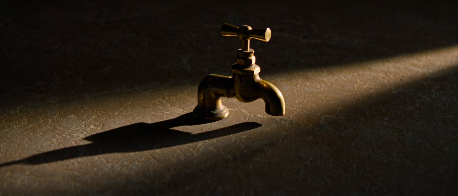 a heavy brass wall tap, its handle still crisp-edged and unworn
