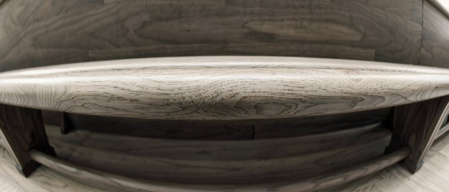 the top rail of a wooden pew worn to a shine by hands