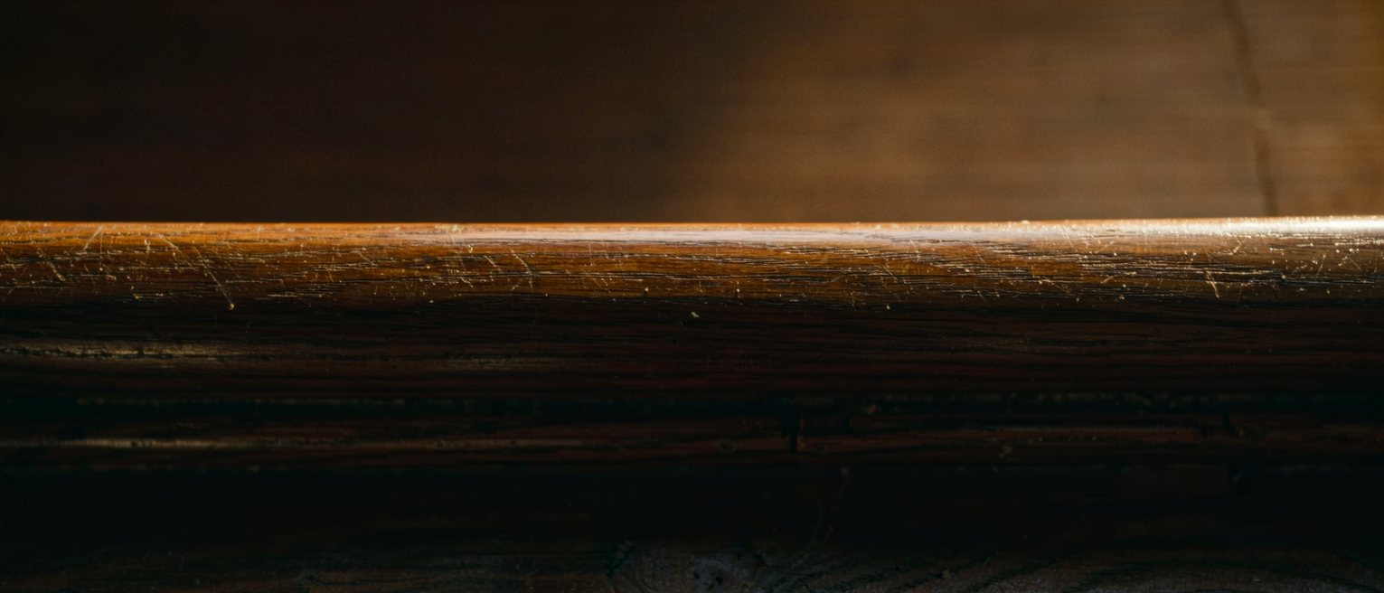 the top rail of a wooden pew worn to a shine by hands