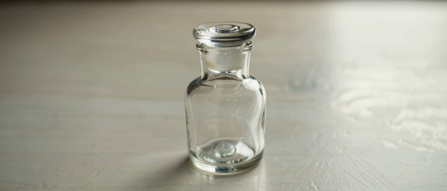 a glass apothecary jar with its ground-glass stopper seated tight, the glass plain and unlabelled