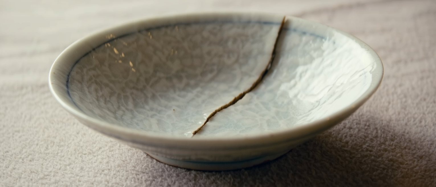 a ceramic bowl whose old break has been glued back together, the join line visible and holding with no piece missing and no gap
