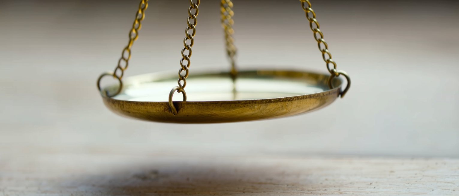 a brass scale pan hanging level and empty, the beam steady