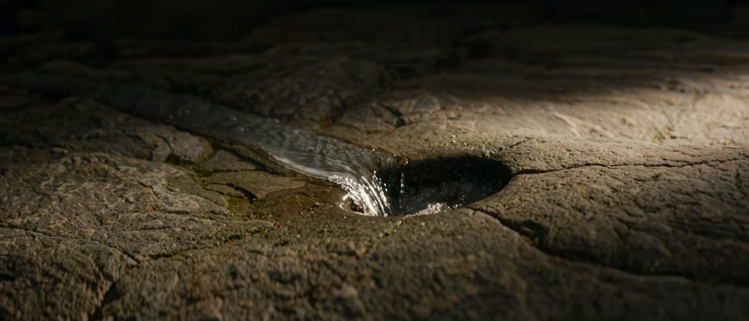 a cold spring running out of bare rock into a stone basin, the water not still