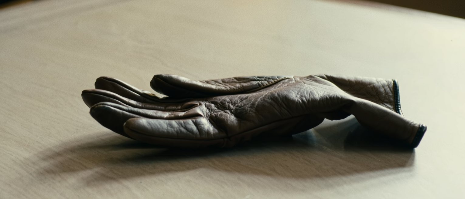 a pair of leather gloves worn thin at the palms and still keeping the shape of the hands