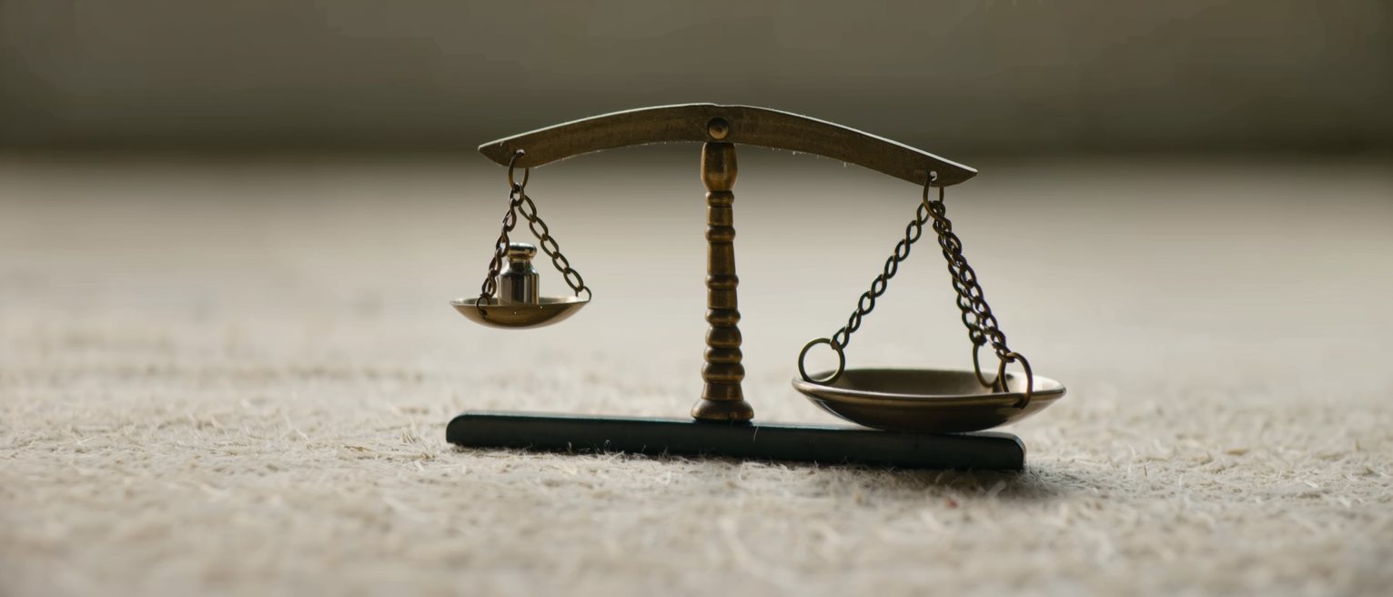 a pair of scales tipped by a single small weight in one pan