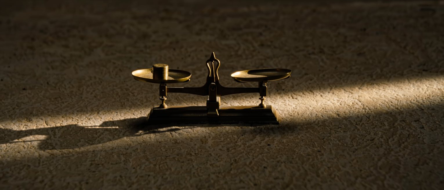 a pair of scales tipped by a single small weight in one pan