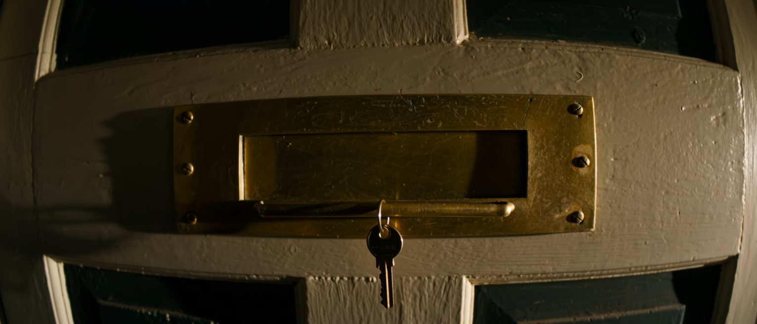 the brass letter plate on a painted door, its spring flap closed flat