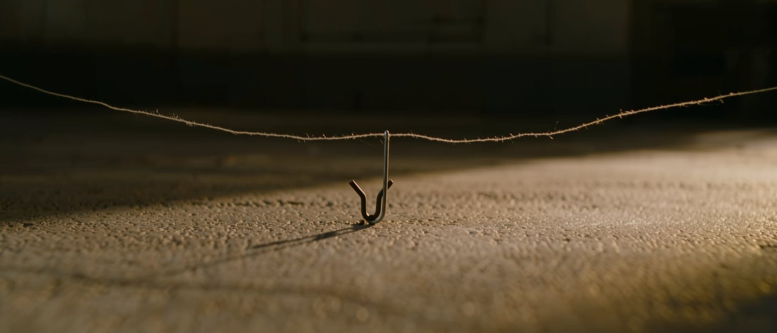 a fine wire run taut between two stakes at ankle height, hooked to a set trigger